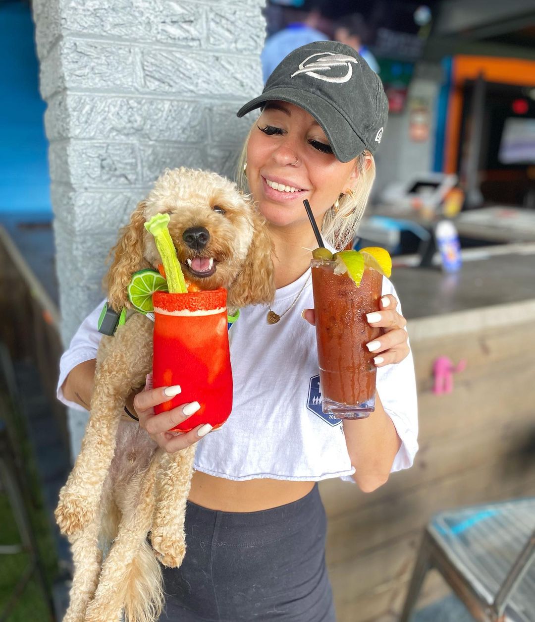 woman holding a dog and 2 drinks